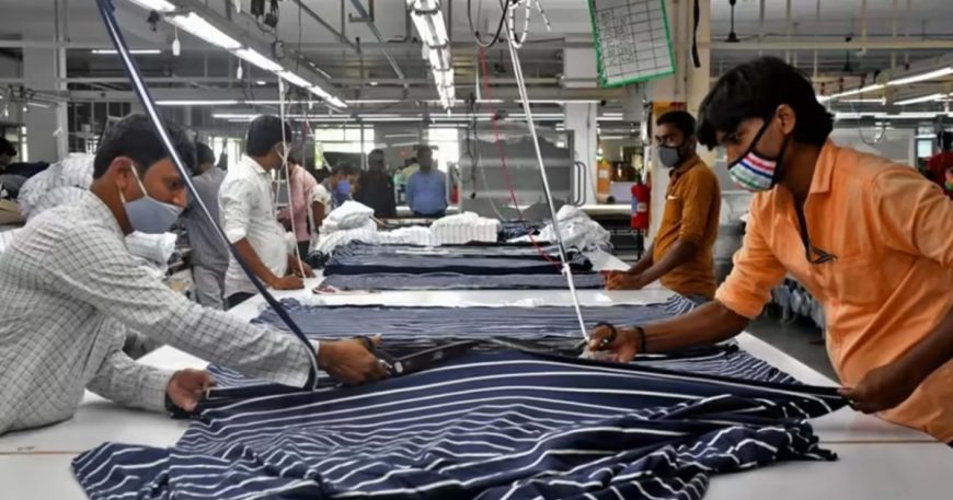 Garment workers handling fabric at a factory production table